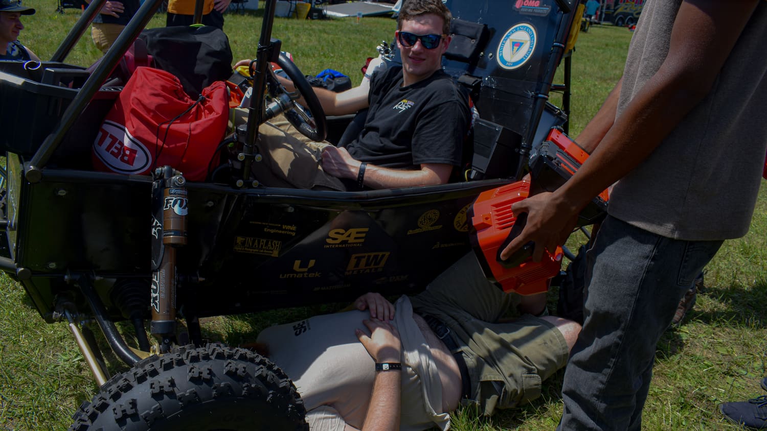 A driver seated in GBR4 while a teammate helps prepare the car